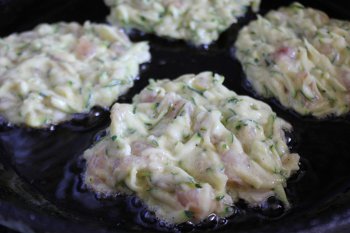 Оладьи из курицы и кабачка жарятся на сковороде с растительным маслом